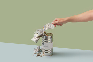 Banknote being pulled out of Savings can by hand.