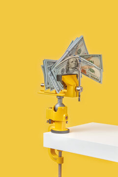 Dollar bills being pressed by clamp tool.