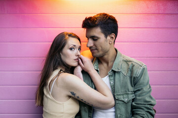 Portrait of a couple against pink wall