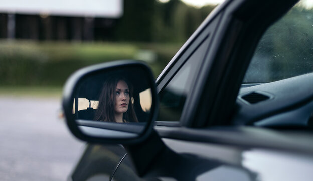 Young woman reflected in side mirror of car at drive-in cinema