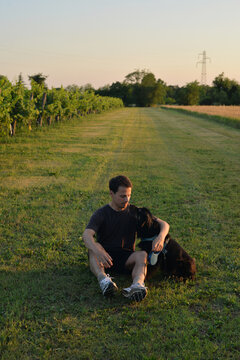 Man hugs his black dog in a dield