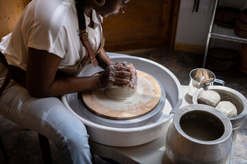 Woman working with clay on the pottery wheel
