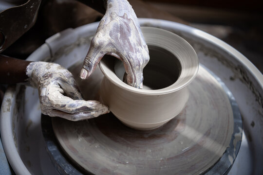 Closeup of woman working with clay on the pottery wheel