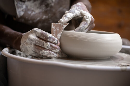 Closeup of woman shaping clay edges on pottery wheel