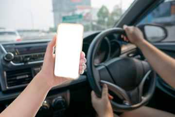 Hand holding smartphone with car driver background