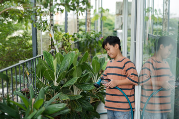 Little gardener watering palm tree with sprinkler