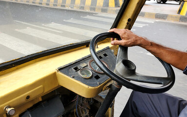 view of Indian Auto Rickshaw driver hand on driving wheel in the road