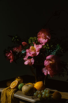 a still life of camellias and fruit on a wooden board 