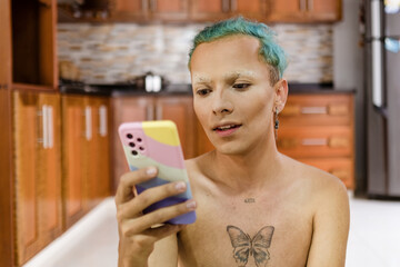 Queer person with makeup looks at his phone