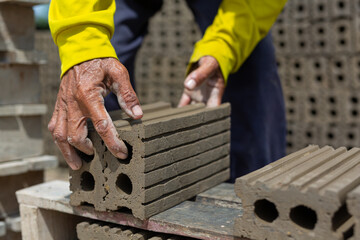 Workers lift hard clay bricks used in construction.