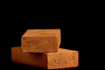 Solid clay bricks used in construction are laid on a black background.