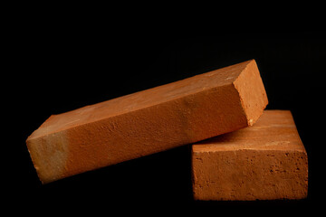 Solid clay bricks used in construction are laid on a black background.