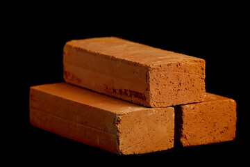 Solid clay bricks used in construction are laid on a black background.