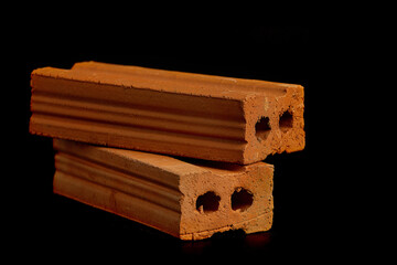 Solid clay bricks used in construction are laid on a black background.