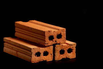 Solid clay bricks used in construction are laid on a black background.