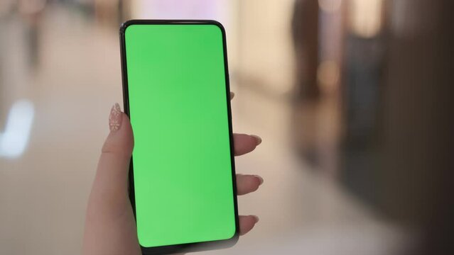 Use green screen for copy space closeup. Chroma key mock-up on smartphone in hand. Woman holds mobile phone