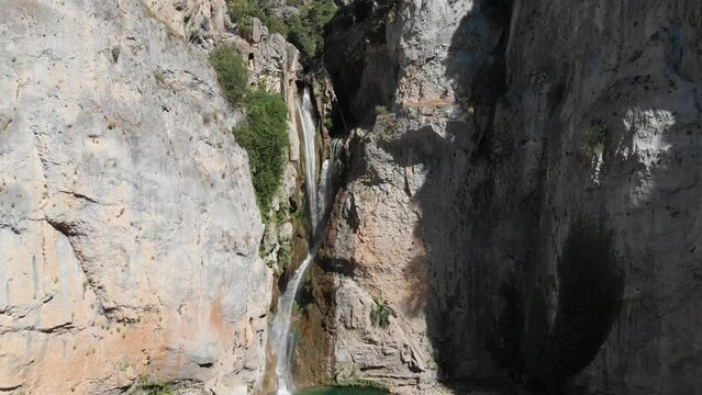 Aerial shot moving to the side, right of beauty in nature. Waterfall between grey cliffs in mountains as crystal clear water falling free.