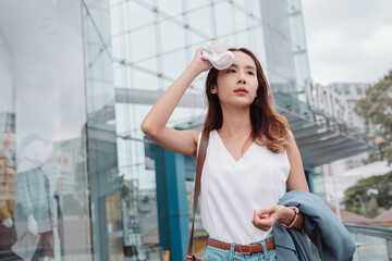 Asian businesswoman facial skin is damaged by UV attack from bright sun light in the modern city near office, Sun cream, sun block concept.