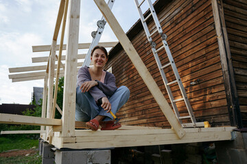 A female carpenter sits on a newly built porch in the backyard