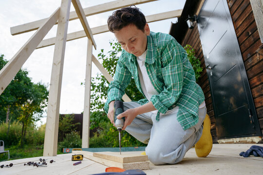 Female carpenter at work with a screwdriver in the backyard