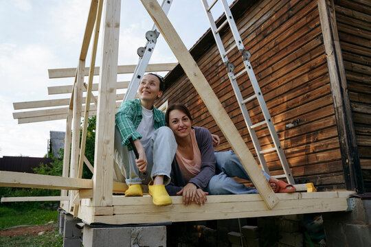 Two women are sitting on a newly built veranda in the backyard