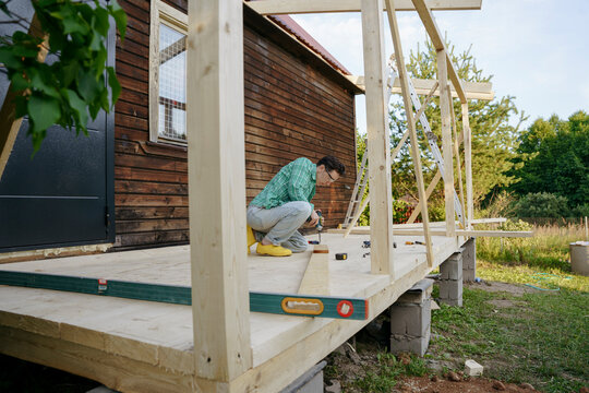 Female carpenter at work with a screwdriver in the backyard