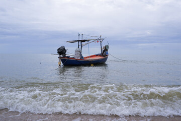 Fototapeta premium Fishermen's boats stop at the beach, where there is sand and waves.
