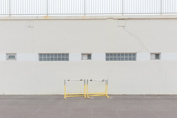 A yellow hurdle in front of a wall with multiple windows.