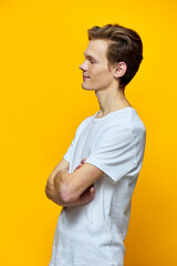 a guy with arms crossed on his chest stands on a yellow background sideways to the camera