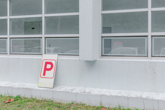 A parking sign in front of a white building.
