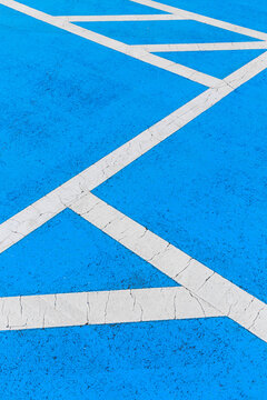 Close-up of white lines drawn in blue parking lot.