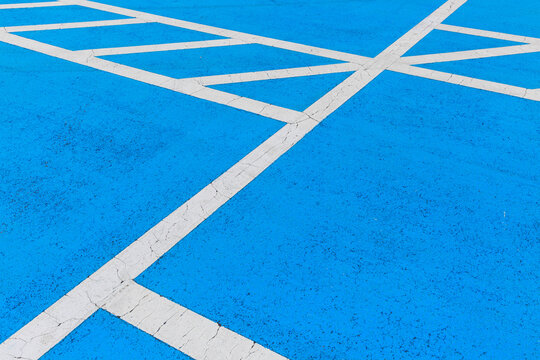 A white line drawn on the floor of a blue parking lot.