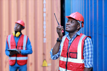 Foreman using tablet and walkie talkie radio control loading containers box. Engineer or worker with safety hat work at container cargo site and checking industrial container cargo freight ship.