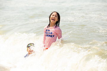 little girl and her sibling having fun with the wave