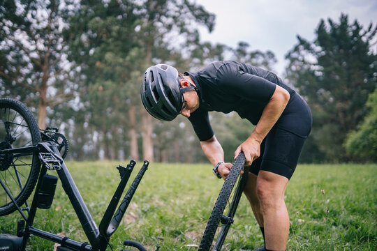 Man fixing wheel of bicycle in countryside