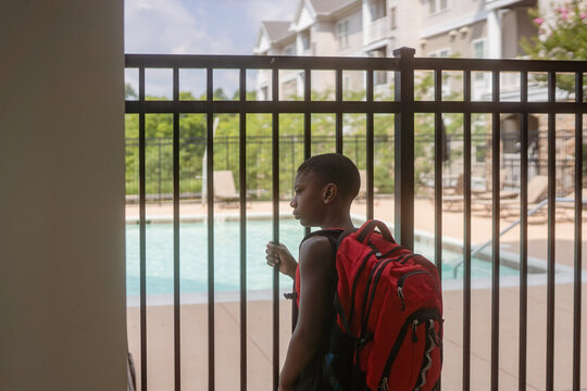Boy peers through bars at locked pool