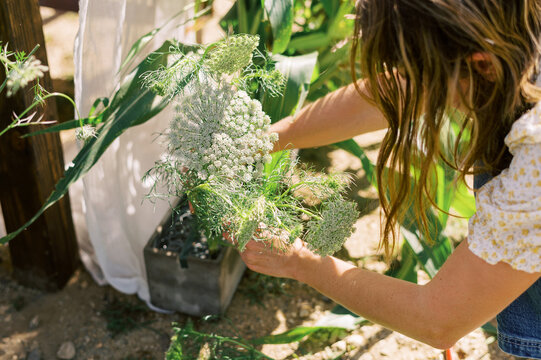 woman arranging flowers and corn stalks for a dinner event on a farm