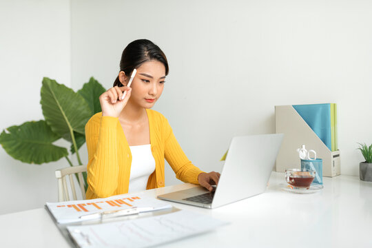 Female freelancer working from home in the morning, holding pen
