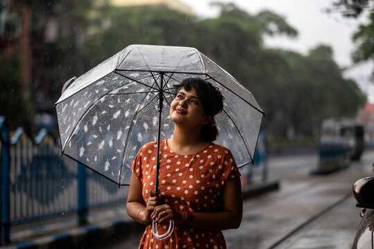 Young woman walking through street in city at monsoon