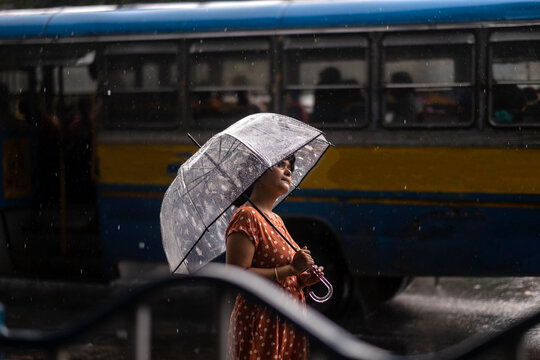 Young woman walking through street in city at monsoon