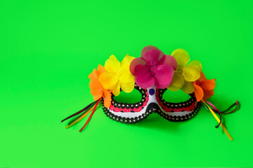 Mexican face mask with flowers and ribbons on the green background. Day of the dead concept