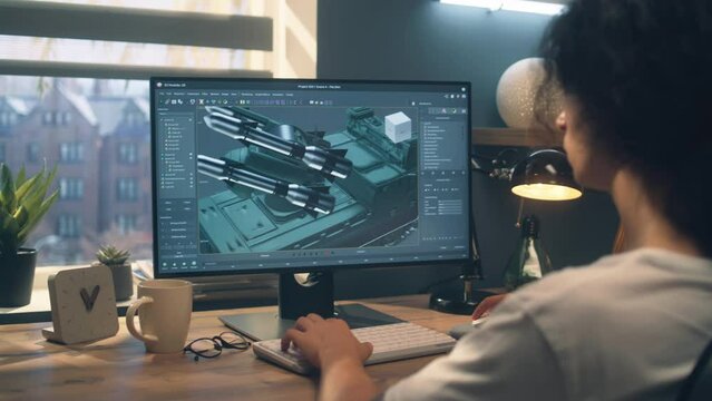Male designer creating 3D model of missile launcher using professional 3D modeling program on computer, while sitting at the table at home and working on freelance