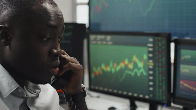 Young adult Black man working in stock trading agency feeling stressed out because of some problems explaining issue to client or colleague on phone call