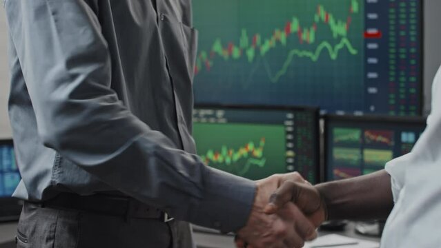 Medium section of unrecognizable ethnically diverse stoke trading advisor and client doing handshake after making deal