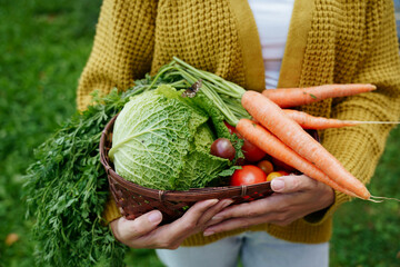 A woman holds a basket of vegetables from her garden