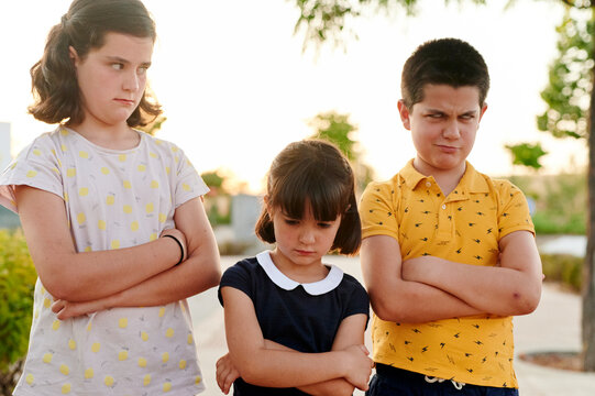 Sulking young siblings standing in a park