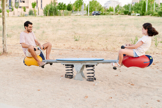Laughing uncle and niece playing on a seesaw