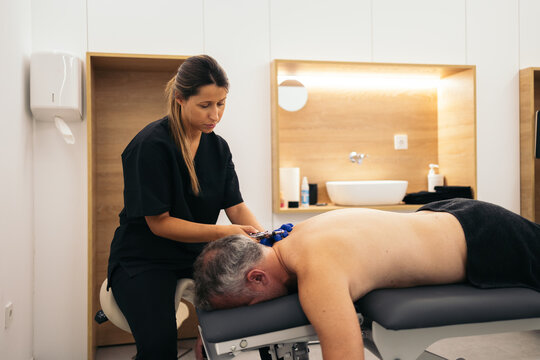 Physiotherapist giving electropuncture treatment to a patient