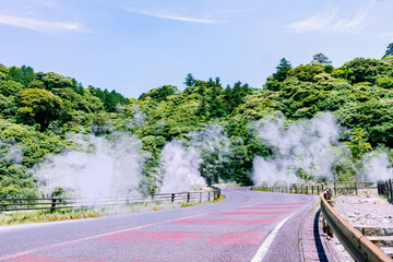 温泉の湯煙が上がる九州の山地を通る道