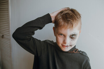Scary boy celebrating halloweenday of the dead terrifying skull face makeup for eyes mouth